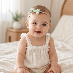 Smiling baby in a small mint bow headband