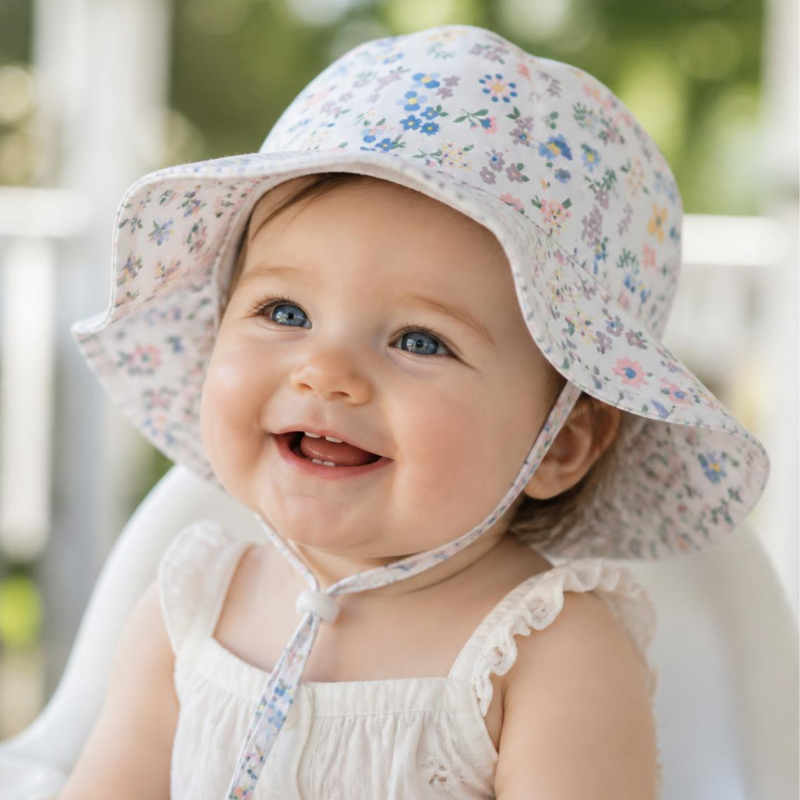 Close up of a smiling baby in a floral wide brim sun hat
