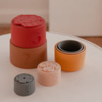 Silicone Baby Stacking Cups Bath & Beach in Earthy — baby hat styled flat lay with nursery accessories