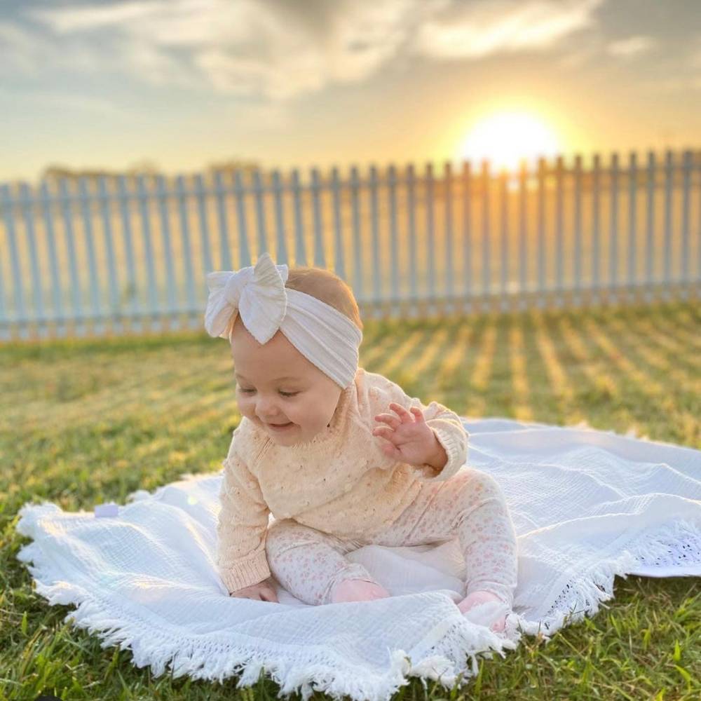 Bowie Double Bow Baby Headband in White — baby headband styled flat lay with nursery accessories