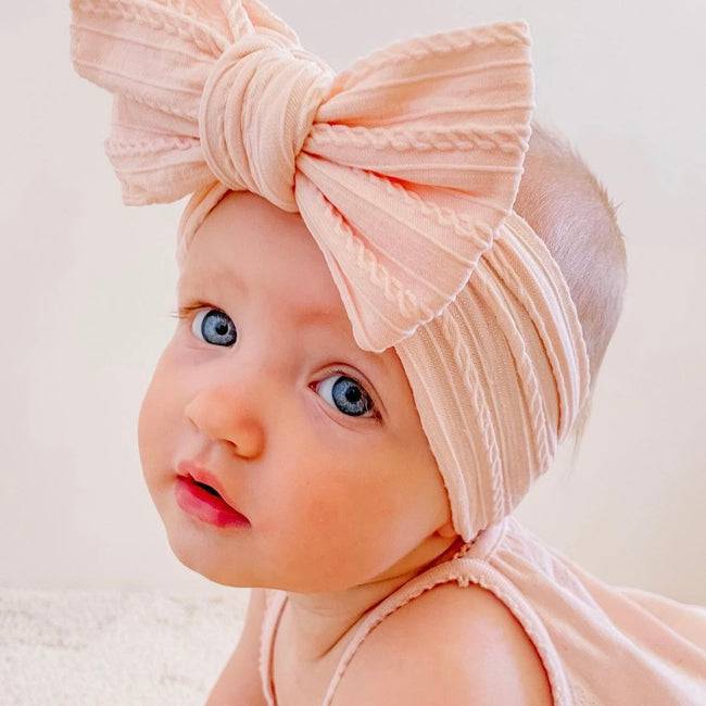 Bowie Double Bow Headband in Coral — baby headband styled flat lay with nursery accessories