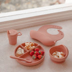 Baby wearing brandy rose baby bib during mealtime — Silicone Baby Feeding Set
