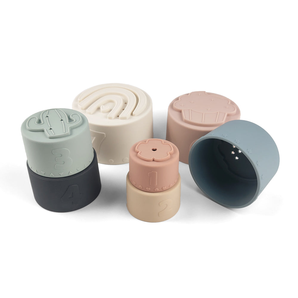 Silicone Baby Stacking Cups Bath & Beach in Pastel — baby hat styled flat lay with nursery accessories