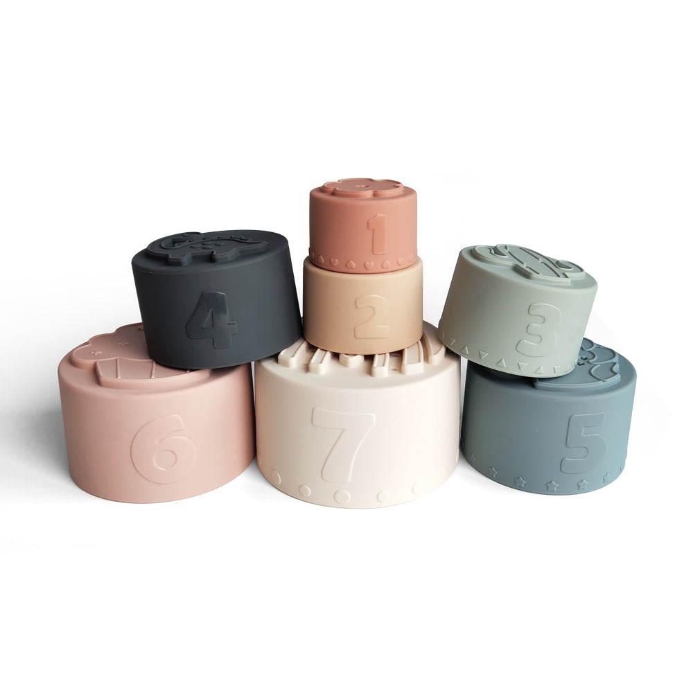Silicone Baby Stacking Cups Bath & Beach in Pastel — baby hat styled flat lay with nursery accessories