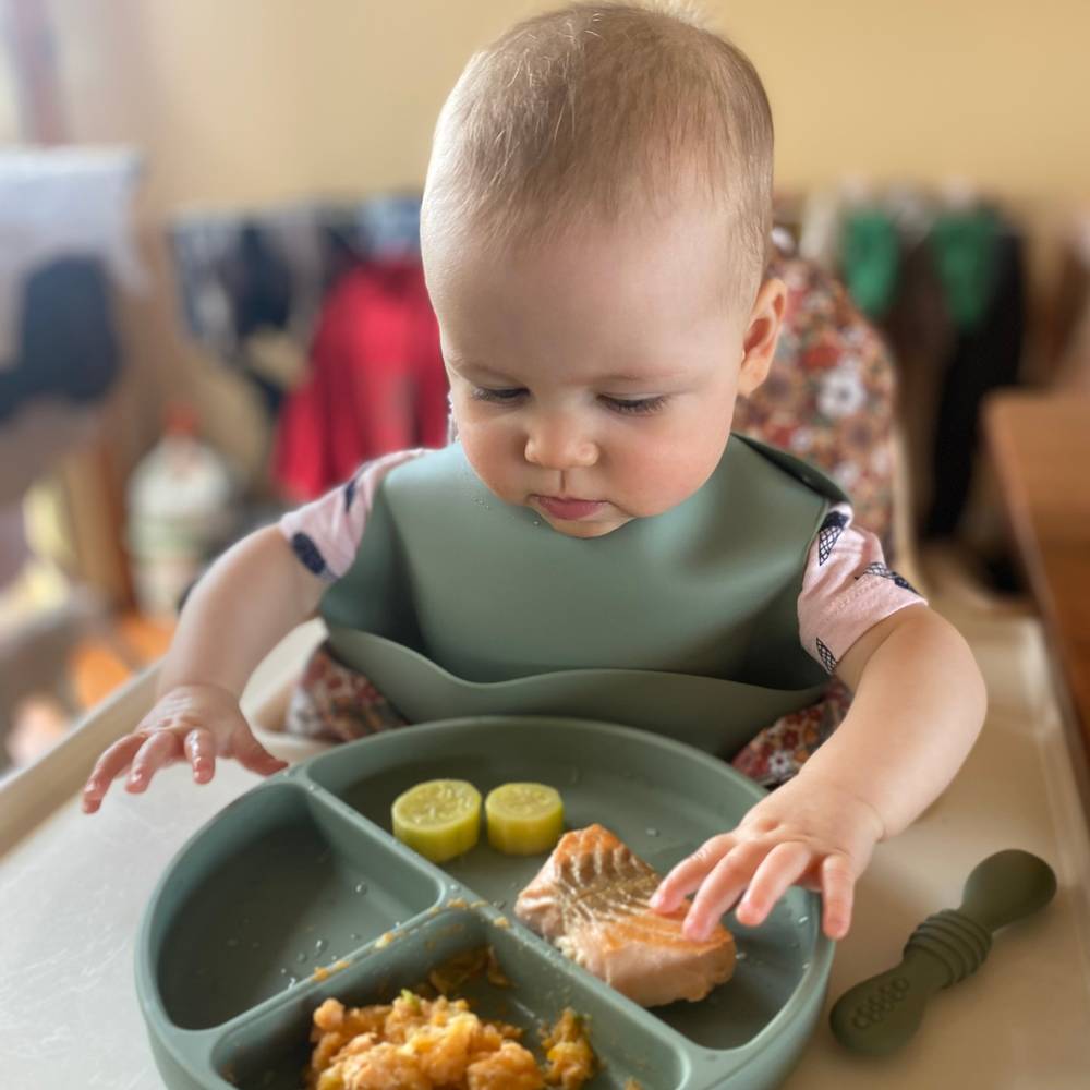 Baby wearing chalet green baby bib during mealtime — Silicone Baby Feeding Set