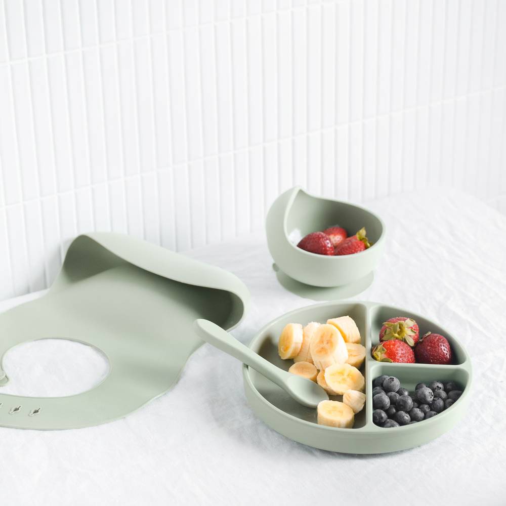 Silicone Baby Feeding Set in Cherry Blossom — baby bib styled flat lay with nursery accessories