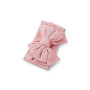 blush pink ribbed knit baby headband with re-tieable oversized double bow, designed for newborns and toddlers