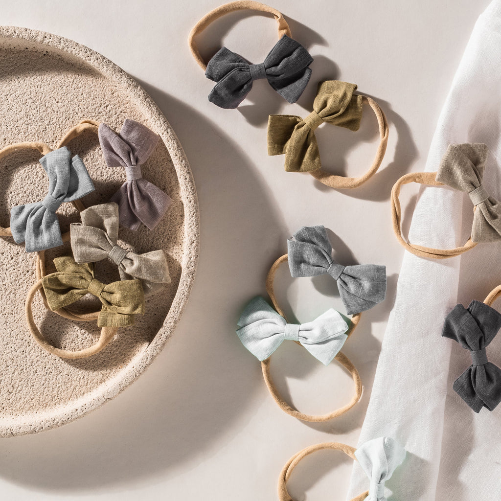 Tinka bow baby headbands in charcoal, olive, sand, grey, light blue and lilac linen bows on soft nylon bands